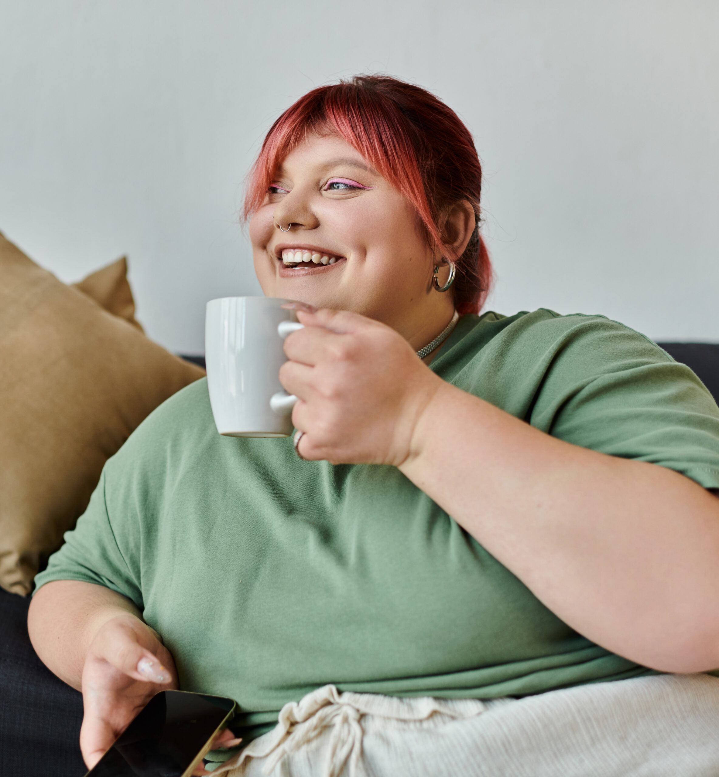 young woman smiling on sofa with cup of tea