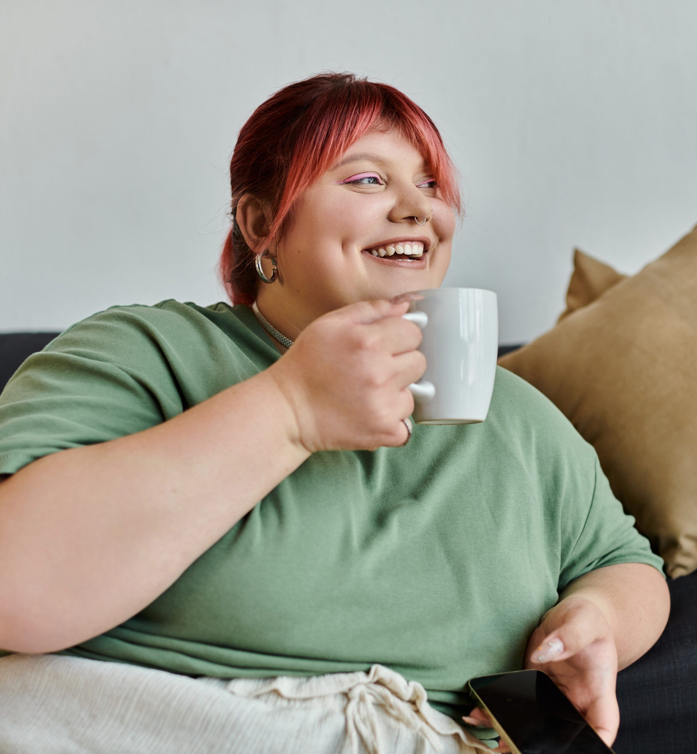 young woman smiling on sofa with cup of tea